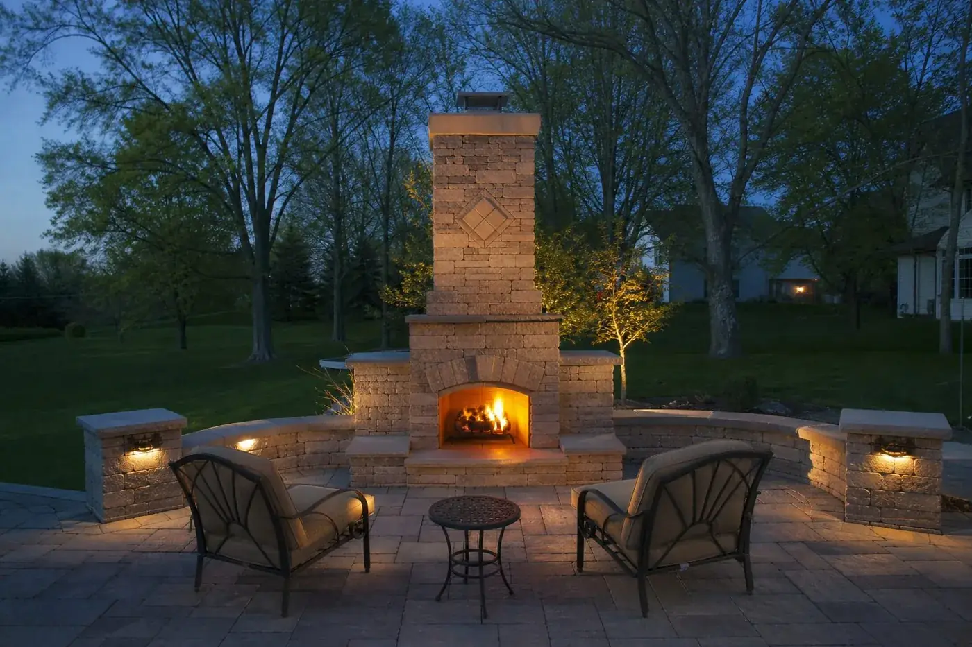 Stone outdoor fireplace lit on a paver patio near Indianapolis, IN