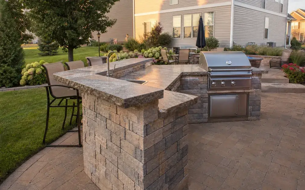 Outdoor kitchen with a built-in grill and stone bar on a paver patio in Indianapolis, IN