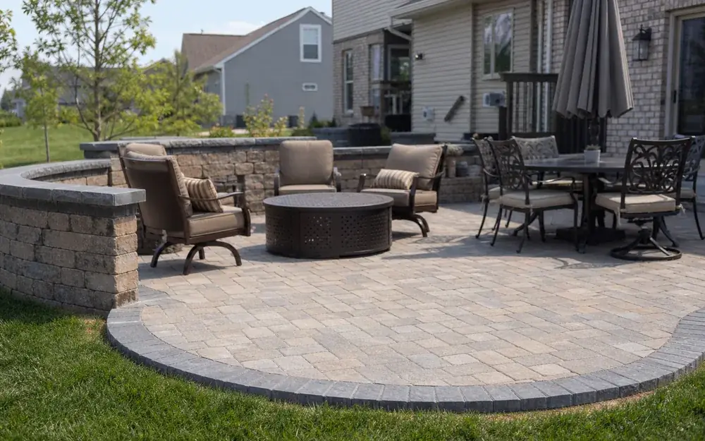 Finished paver patio with a fire table and seat wall in an Indianapolis, IN backyard